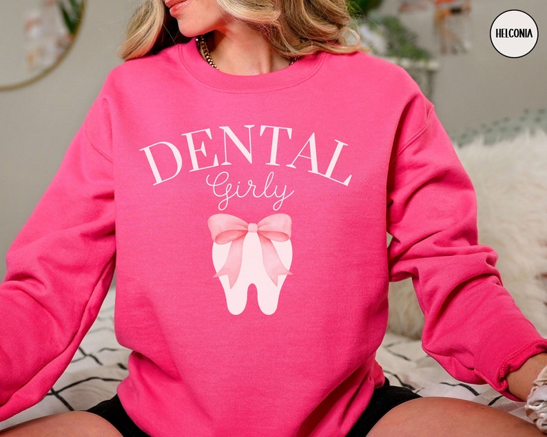 May include: Pink sweatshirt with the text "Dental Girly" and a pink bow on a white tooth graphic.