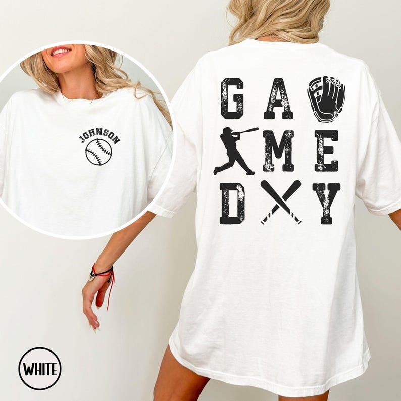 May include: White t-shirt with a baseball graphic and the text "GAME DAY" on the back. The front of the shirt has the text "JOHNSON" and a baseball graphic.