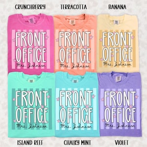 Puede incluir: Seis camisetas en colores crunchberry, terracotta, banana, island reef, chalky mint y violeta. Cada camiseta presenta rayas verticales, el texto "FRONT OFFICE" en blanco y "Mrs. Johnson" en letra cursiva negra, decorado con pequeñas estrellas rosas.