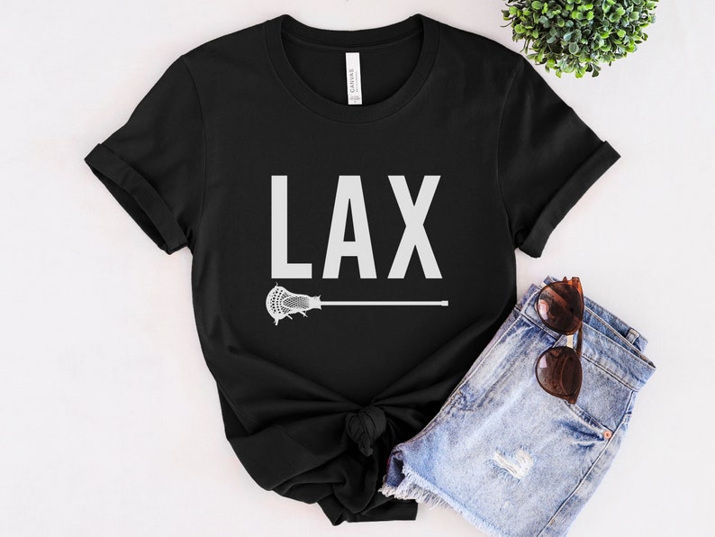 May include: Black t-shirt with white text that says "LAX" and a white lacrosse stick graphic.