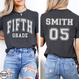 May include: A dark grey heather t-shirt with the text "FIFTH GRADE" on the front and the text "SMITH 05" on the back.