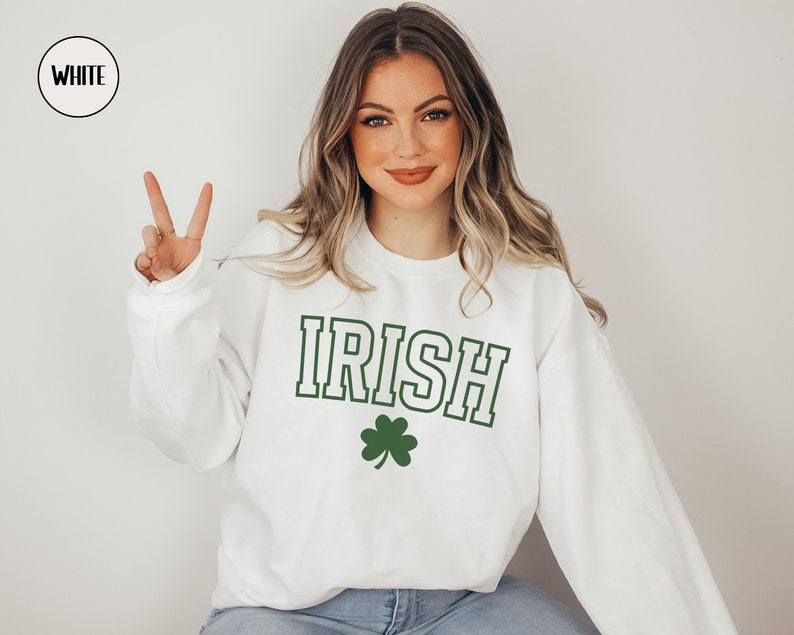 Op de afbeelding: Wit sweatshirt met het woord "IRISH" in groene en zwarte letters en een groene klaver.