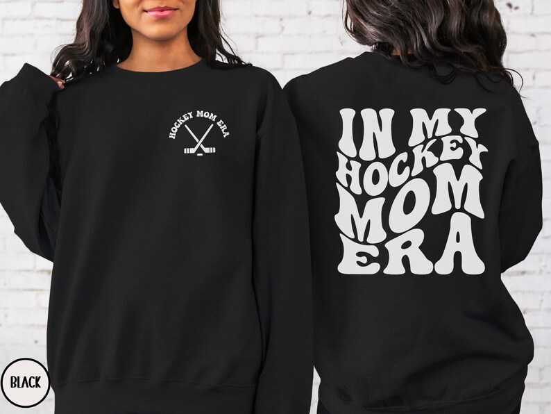 May include: Black sweatshirt with white text that says "In My Hockey Mom Era" on the back and a small hockey stick graphic on the front.
