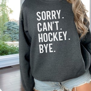 May include: Gray sweatshirt with the text "SORRY. CAN'T. HOCKEY. BYE." in white.