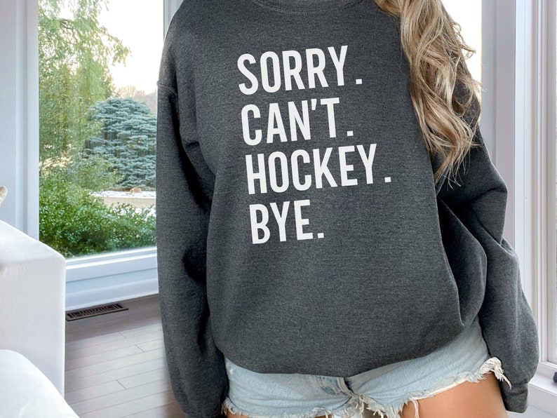 May include: Gray sweatshirt with the text "SORRY. CAN'T. HOCKEY. BYE." in white.