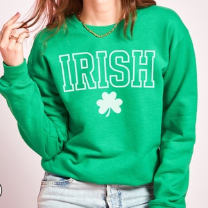Op de afbeelding: Groen sweatshirt met het woord "IRISH" in witte letters en een wit klavertje vier.