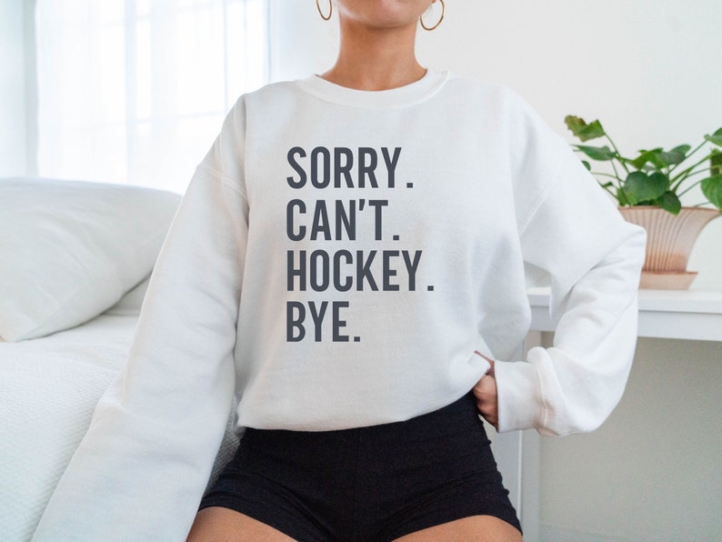 May include: White sweatshirt with the text "SORRY. CAN'T. HOCKEY. BYE." printed in black.