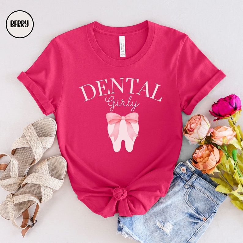 May include: Pink t-shirt with the text "DENTAL Girly" and a pink tooth with a pink bow on it.