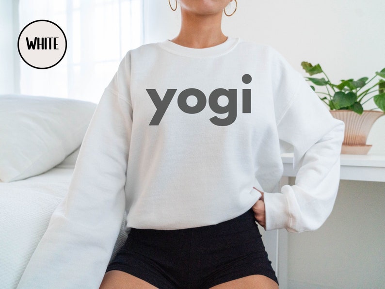 Może przedstawiać: Biała bluza z nadrukiem słowa "yogi" w kolorze czarnym z przodu.