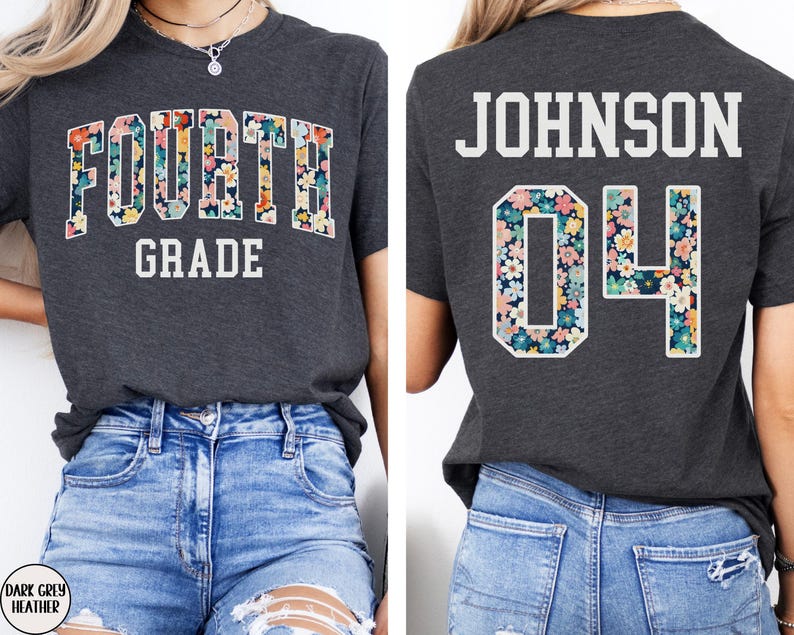 May include: Dark grey heather t-shirt with "FOURTH GRADE" in white text. The word "FOURTH" is filled with a floral pattern. The back of the shirt has the name "JOHNSON" and the number "04" in a floral pattern.