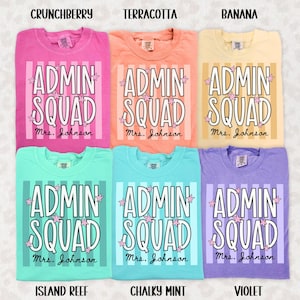 May include: Six t-shirts in crunchberry pink, terracotta orange, banana yellow, island reef green, chalky mint, and violet. Each shirt features vertical stripes, the text "ADMIN SQUAD" in white, small pink stars, and the name "Mrs. Johnson" in black.