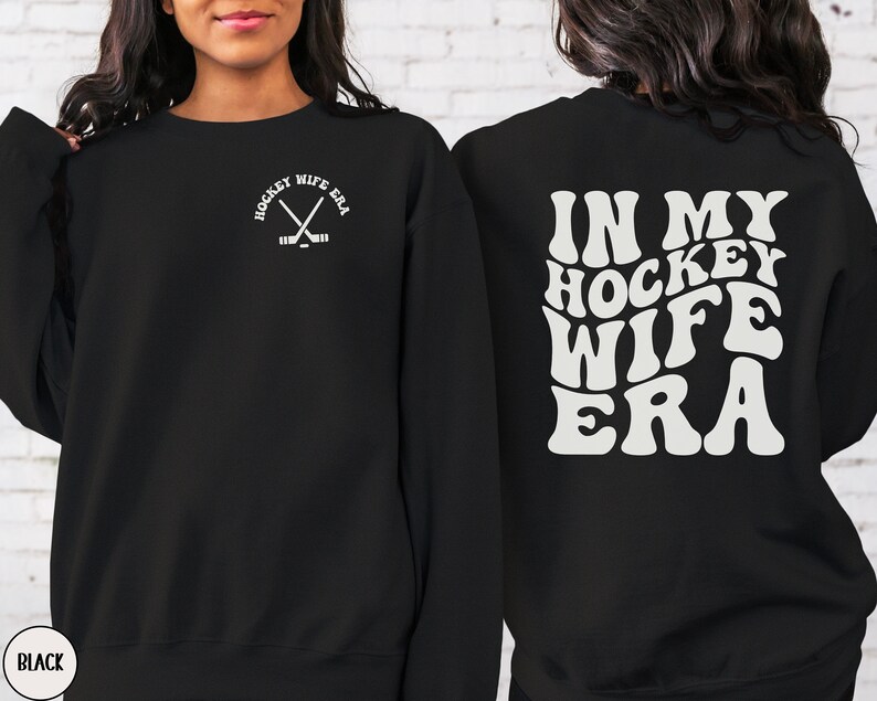 Pu&ograve; includere: Felpa nera con il testo "Hockey Wife Era" in un font retr&ograve; sul retro. La parte anteriore della felpa ha una piccola grafica di bastoni da hockey incrociati con il testo "Hockey Wife Era" in un font pi&ugrave; piccolo.