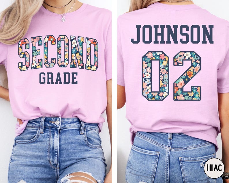 Puede incluir: Camiseta rosa claro con las palabras "SECOND GRADE" en un dise&ntilde;o floral en la parte delantera. La parte trasera de la camiseta tiene el nombre "JOHNSON" y el n&uacute;mero "02" en un dise&ntilde;o floral.