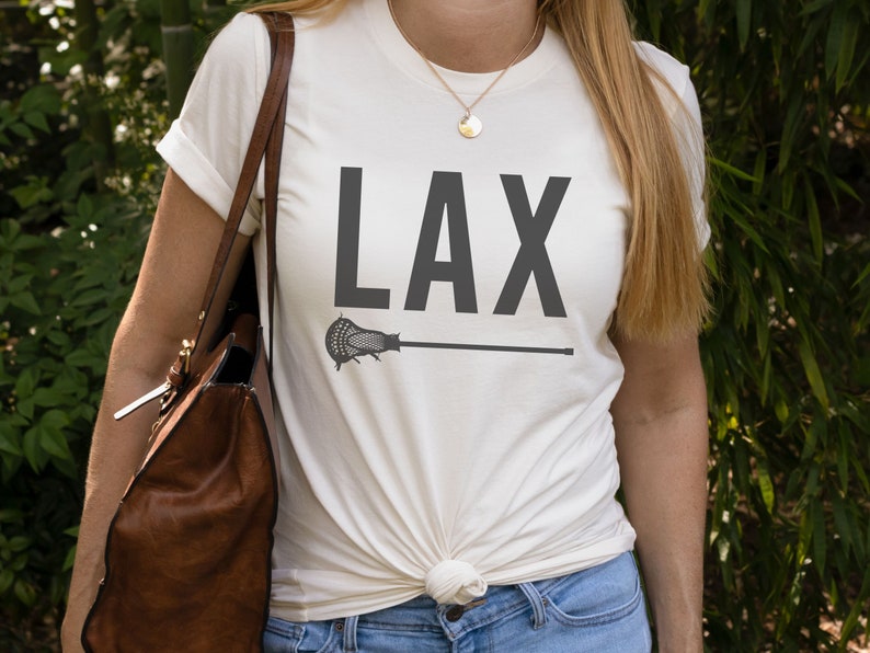 May include: White t-shirt with a black graphic of a lacrosse stick and the word "LAX" printed on it.