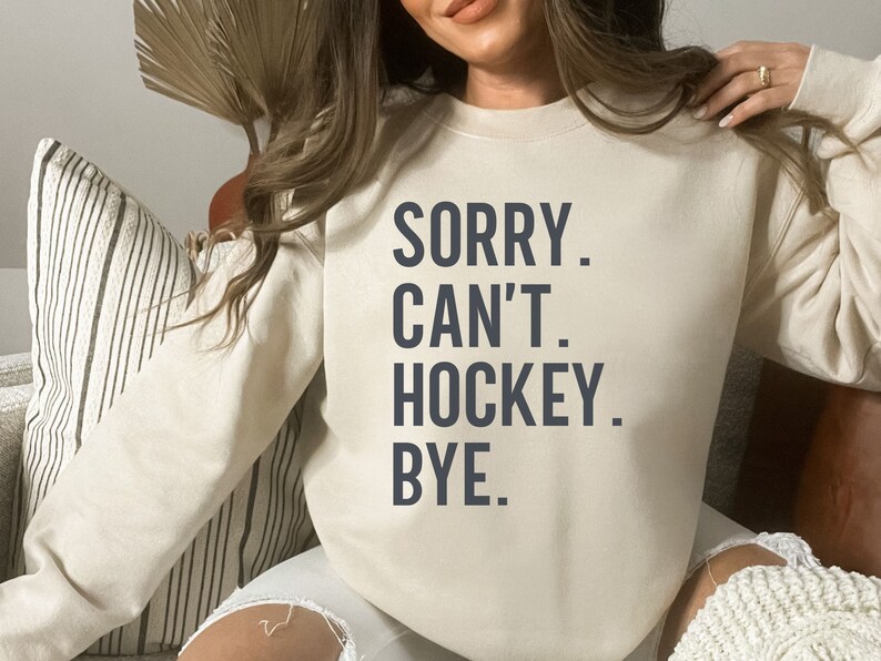 May include: A white sweatshirt with the text "SORRY. CAN'T. HOCKEY. BYE." printed in dark blue.