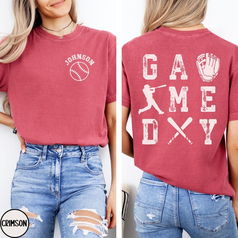 May include: Red t-shirt with the text "Johnson" and a baseball graphic on the front. The back of the shirt has the text "Game Day" with a baseball player graphic and crossed bats.