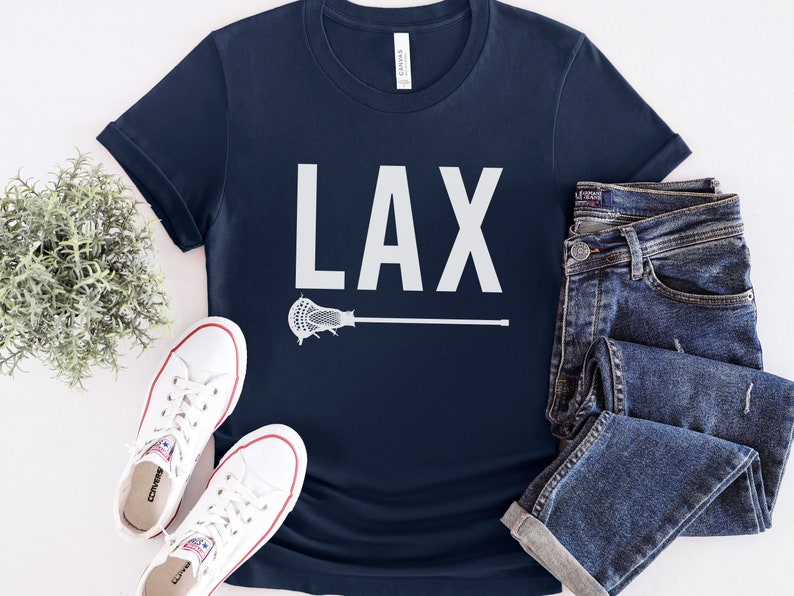 May include: A navy blue t-shirt with a white graphic of a lacrosse stick and the word "LAX" printed on the front.