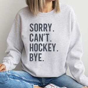 May include: Gray sweatshirt with the text "SORRY. CAN'T. HOCKEY. BYE." printed in dark gray.