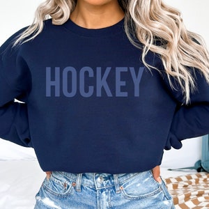 May include: A navy blue sweatshirt with the word "HOCKEY" printed in a light blue color on the front.