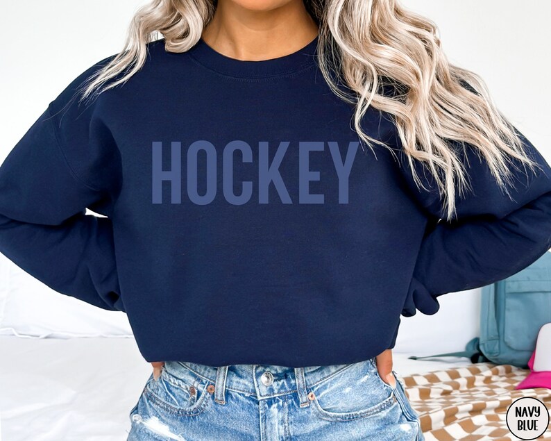 May include: A navy blue sweatshirt with the word "HOCKEY" printed in a light blue color on the front.