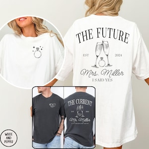 May include: Two matching t-shirts, one white and one dark gray, with a wedding theme. The white shirt says "The Future" with a champagne glass and ring design, "EST 2024", "Mrs. Miller", and "I Said Yes". The gray shirt says "The Current" with a champagne glass and ring design, "EST 2024", "Mr. Miller", and "Can't Believe She Said Yes".