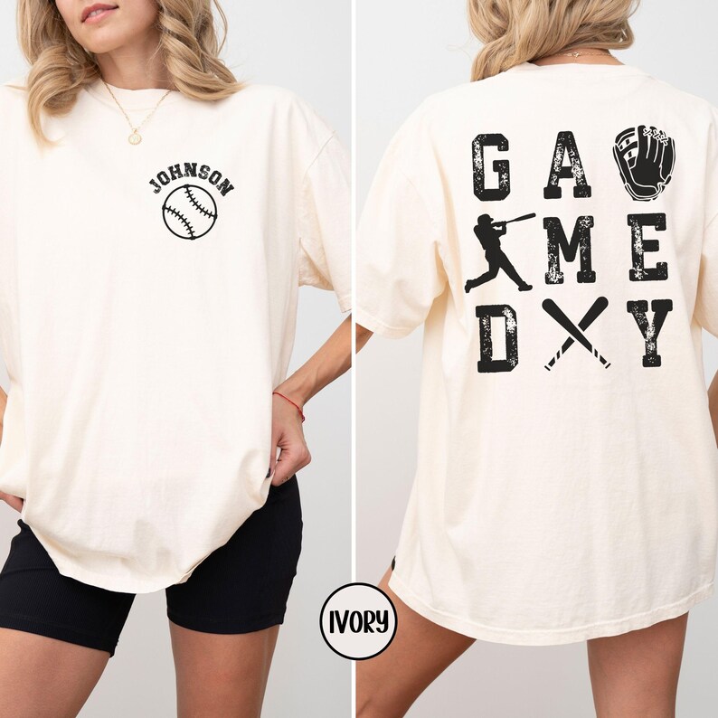 May include: Ivory t-shirt with a baseball graphic and the text "JOHNSON" on the front. The back of the shirt has the text "GAME DAY" with a baseball player graphic and a baseball glove graphic.