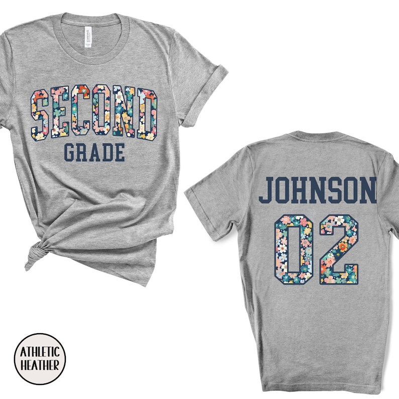 Puede incluir: Camiseta gris jaspeado con "SECOND GRADE" en un dise&ntilde;o floral en la parte delantera. La parte trasera de la camiseta muestra "JOHNSON" y el n&uacute;mero "02" en un patr&oacute;n floral a juego. La camiseta est&aacute; hecha de material Athletic Heather.