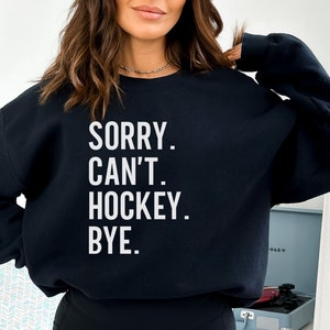 May include: Black sweatshirt with white text that reads "SORRY. CAN'T. HOCKEY. BYE."