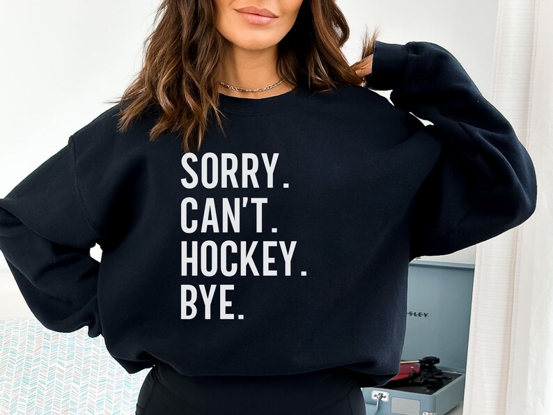 May include: Black sweatshirt with white text that reads "SORRY. CAN'T. HOCKEY. BYE."