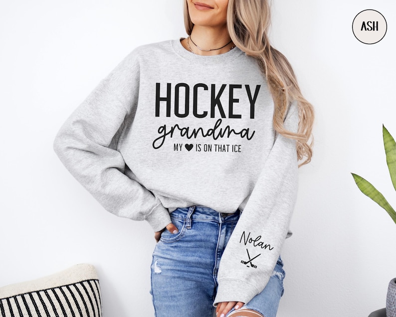 May include: Gray sweatshirt with the text "HOCKEY grandma MY &hearts; IS ON THAT ICE" and the name "Nolan" printed on the sleeve with a hockey stick graphic.