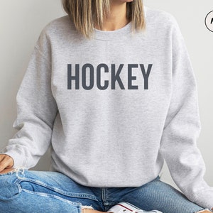 May include: A gray sweatshirt with the word "HOCKEY" printed in dark gray on the front.
