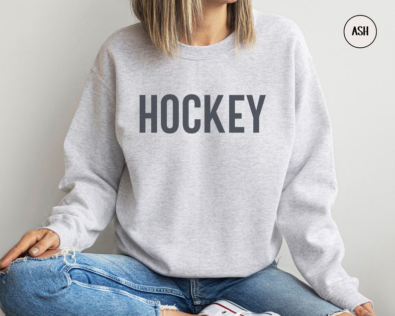May include: A gray sweatshirt with the word "HOCKEY" printed in dark gray on the front.