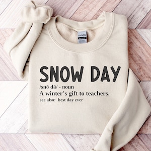 May include: A beige sweatshirt with the text "SNOW DAY" in black, defined as "A winter's gift to teachers."