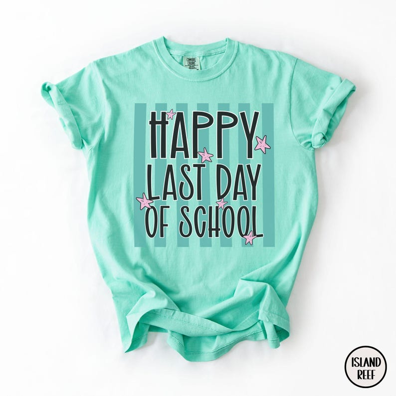 May include: A light turquoise t-shirt with the text "HAPPY LAST DAY OF SCHOOL" in black, with pink star accents. The text is set against a background of vertical stripes. The shirt has short sleeves and a crew neck.