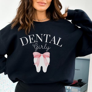 May include: Black sweatshirt with the text "Dental Girly" and a pink bow on a white tooth graphic.
