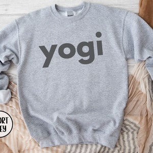 Może przedstawiać: Szara bluza z nadrukiem słowa "yogi" w kolorze czarnym na przodzie.