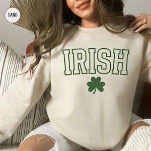 Op de afbeelding: Een cr&egrave;mekleurig sweatshirt met het woord "IRISH" in groen met een witte omlijsting. Onder het woord staat een groen klavertje vier.