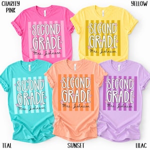 May include: Five short-sleeved crew neck t-shirts in charity pink, yellow, teal, sunset, and lilac. Each shirt features a vertical striped background with the text SECOND GRADE and Mrs. Johnson in white, accented by small pink stars.