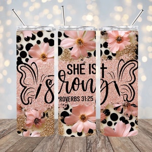 May include: A stainless steel tumbler with a pink and black floral design. The tumbler has a rose gold glitter finish and features the text "She is strong" with the Bible verse "Proverbs 31:25".