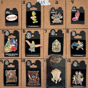 May include: A collection of Disney character pins displayed on a corkboard. The pins feature characters like Stitch, Dumbo, and Mickey Mouse. Each pin is attached to a black backing card with the Disney logo and website address.