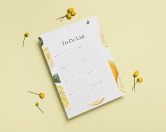 Puede incluir: Un bloc de notas blanco con una lista de tareas con un diseño de limón en acuarela. El bloc de notas tiene secciones para cada día de la semana y un espacio para notas. Flores amarillas y rodajas de limón decoran los bordes.