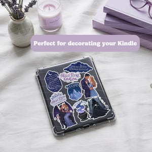 May include: A clear protective case for an e-reader featuring a collection of fantasy-themed stickers. The stickers display illustrations of a couple, a mountain range, a cauldron, and text including Hello Feyre Darling, Velaris, and High Lady.