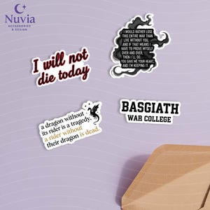 May include: A collection of white stickers with black text and designs. One sticker reads "I will not die today" in a bold font. Other stickers feature quotes and a dragon illustration. The stickers are on a light purple surface.