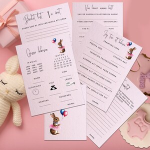 Puede incluir: Un conjunto de tarjetas de baby shower con ilustraciones de conejitos, un conejito de peluche y un regalo envuelto sobre un fondo rosa. Las tarjetas presentan indicaciones para rellenar y un calendario. El tema es baby shower o anuncio de bebé.