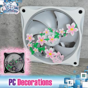 May include: White computer fan decorated with pink and white cherry blossoms and a pink butterfly. The fan blades are gray. The text "PC Decorations" is at the bottom of the image.
