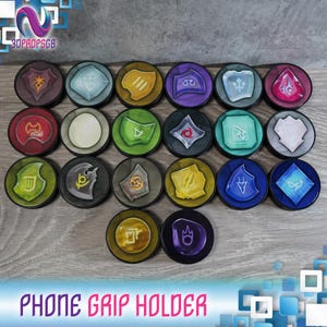 Könnte beinhalten: Ein Set mit 18 bunten Handy-Griffhaltern mit verschiedenen Symbolen und Designs. Jeder Halter ist rund und hat ein anderes Motiv, darunter ein Schwert, ein Stern, eine Mondsichel und ein Blitz. Die Halter sind aus strapazierfähigem Material gefertigt und so konzipiert, dass sie leicht zu greifen und zu verwenden sind.