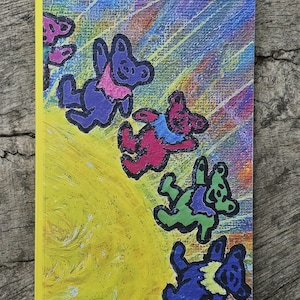 May include: A yellow-bound notebook featuring a colorful illustration of dancing bears. The bears are depicted in various colors, including purple, red, green, and blue, with pink and blue accents. The background has a yellow and rainbow gradient.