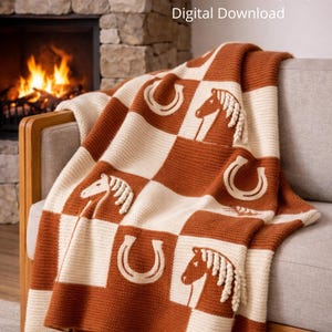 Puede incluir: Una manta tejida con un patrón de tablero de ajedrez en crema y marrón óxido. El diseño presenta caballos y herraduras. La manta está sobre un sofá. El texto en la parte superior dice "KNITTING PATTERN (PDF) Digital Download."