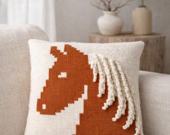 May include: A square, off-white knitted pillow with a horse head design in shades of brown and cream. The horse's mane is made of cream-colored, textured yarn. The text "KNITTING PATTERN (PDF) Digital Download" is at the top.