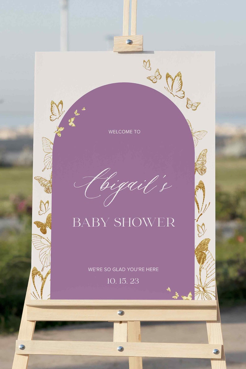 Puede incluir: Un cartel de bienvenida morado y blanco con mariposas doradas y el texto "Bienvenido al baby shower de Abigail. Estamos encantados de que est&eacute;s aqu&iacute;. 10.15.23".